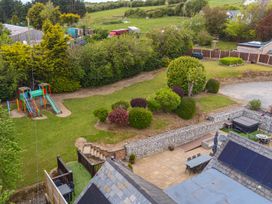 A garden with a playground and seating area at Arosfa in Axton near Trelawynd