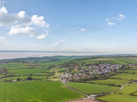 An aerial view of fields and houses near the water at Arosfa in Axton near Trelawynd