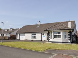 A detached house with a tiled roof a garage and a lawn at SeaShells in Castlerock