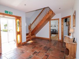 A hallway with tiled floor wooden staircase and a wooden console table with a lamp at SeaShells in Castlerock