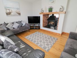A living room with two gray sofas a television a fireplace and a rug on a wooden floor at SeaShells in Castlerock