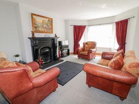A living room with red leather sofas a black fireplace a television and red curtains at SeaShells in Castlerock