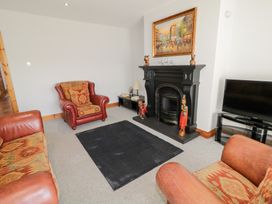 A living room with leather armchairs a black fireplace a television and a rug at SeaShells in Castlerock