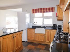 A kitchen with wooden cabinets a white refrigerator a stove a sink and a window with a red and orange striped blind at SeaShells in Castlerock