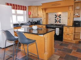 A kitchen with wooden cabinets black countertops a kitchen island with two stools a stove and a refrigerator at SeaShells in Castlerock