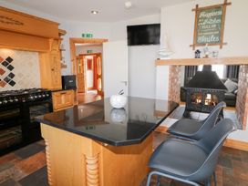 A kitchen with a black countertop island two gray chairs a black stove a fireplace and a wall sign at SeaShells in Castlerock