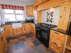 A kitchen with wooden cabinets a black stove a farmhouse sink and a tiled floor at SeaShells in Castlerock