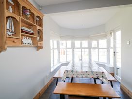A dining area with a picnic style table and benches near large windows at SeaShells in Castlerock