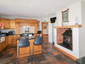 A kitchen with wooden cabinets island with two stools and a fireplace at SeaShells Castlerock