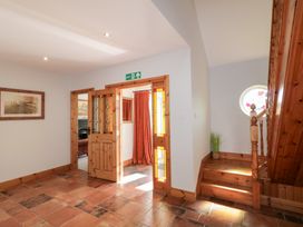 A hallway with tiled floor wooden staircase and an open wooden door with stained glass at SeaShells in Castlerock