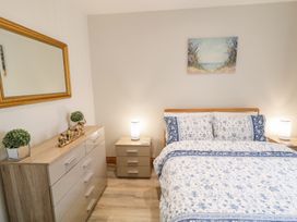 A bedroom with a bed with floral bedding two bedside tables with lamps a chest of drawers with potted plants and elephant figurines and a mirror on the wall at SeaShells in Castlerock