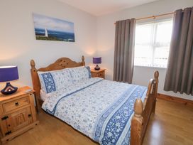 A bedroom with a double wooden bed floral bedding wooden bedside tables and a window with curtains at SeaShells in Castlerock