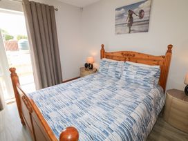 A bedroom with a wooden bed blue and white bedding two lamps on bedside tables and a beach picture on the wall at SeaShells in Castlerock