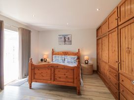 A bedroom with a wooden bed in the center flanked by two round bedside tables with lamps and a large wooden wardrobe on the right at SeaShells in Castlerock