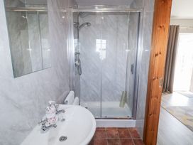 A bathroom with a sink and a soap dispenser next to a glass shower enclosure at SeaShells in Castlerock