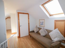 A hallway with a sofa with cushions a skylight window and white doors at SeaShells in Castlerock