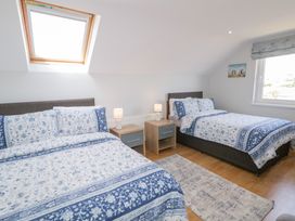 A bedroom with two beds with blue and white bedding two bedside tables with lamps a window and a skylight at SeaShells in Castlerock