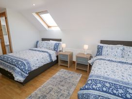 A bedroom with two beds blue and white bed linens two bedside tables with lamps and a skylight window at SeaShells in Castlerock