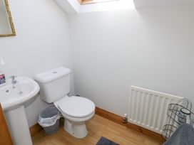A bathroom with a white toilet sink a trash bin and a radiator at SeaShells in Castlerock