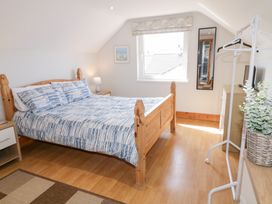 A bedroom with a wooden bed with blue patterned bedding a window a mirror a chest of drawers and a clothing rack at SeaShells in Castlerock