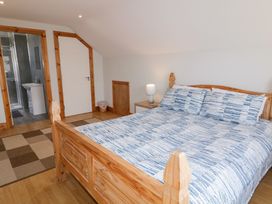 A bedroom with a wooden bed and blue patterned bedding next to a nightstand with a lamp and an adjoining bathroom at SeaShells in Castlerock