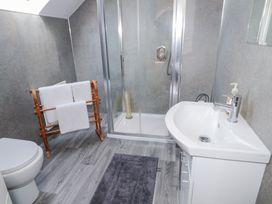 A bathroom with a shower enclosure a white sink a toilet and a wooden towel rack with towels at SeaShells in Castlerock