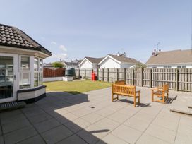 A backyard with tiled patio, two wooden benches, grass area, and surrounding houses at SeaShells in Castlerock