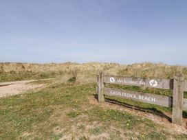 A wooden sign saying welcome to castlerock beach with grass and sand dunes in the background at SeaShells in Castlerock
