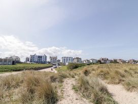A sandy path through grass dunes leading to buildings under a clear sky at SeaShells in Castlerock