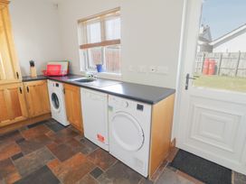 A utility room with washing machine dishwasher dryer wooden cabinets and a door leading outside at SeaShells in Castlerock