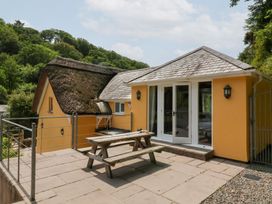 An outdoor area with a thatched roof and a garden table at Old Maids Cottage in Woolacombe