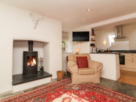 A living room with a fireplace and television at Old Maids Cottage in Woolacombe