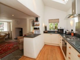 A kitchen with a stove, microwave, and cabinets at Old Maids Cottage in Woolacombe