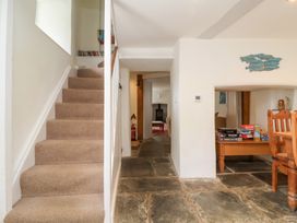 A hallway with stairs and a table with board games at Old Maids Cottage in Woolacombe