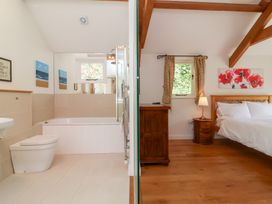 A bathroom with a bathtub and toilet and a bedroom with a bed and nightstand at Old Maids Cottage in Woolacombe
