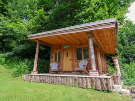 A wooden cabin with chairs on the porch at Old Maids Cottage in Woolacombe