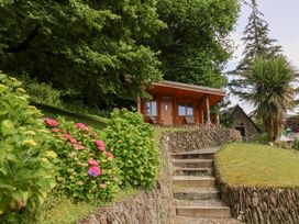 A garden with a cabin and flowers at Old Maids Cottage in Woolacombe
