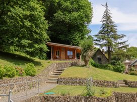 A wooden cabin surrounded by trees and grass at Old Maids Cottage in Woolacombe
