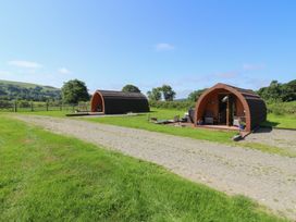 Two glamping pods with outdoor seating in a grassy area at Bwthyn Bach Brefi