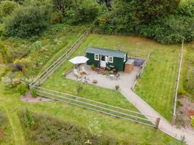 A green cabin with seating and an umbrella at Onnen in Oakford near Aberaeron