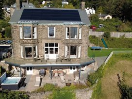 An outdoor area with a house, spa, dining table and lawn at Victoria Mount in Grange-Over-Sands