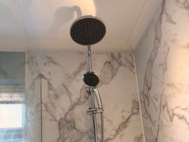 A shower with a rain shower head and handheld shower in Honeybees Haven Hunstanton