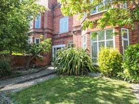 A garden with green grass plants and trees next to a red brick building at Royal Victoria House in Scarborough