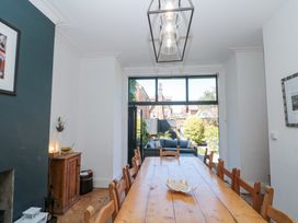 A dining room with a wooden table and chairs leading to a garden with outdoor seating at Royal Victoria House in Scarborough
