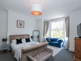 A bedroom with a bed a blue sofa a wooden dresser and a large window at Royal Victoria House in Scarborough