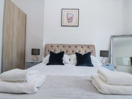 A bedroom with a bed with black pillows two bedside tables with lamps a large mirror and folded towels at Royal Victoria House in Scarborough