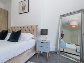 A bedroom with a bed with pillows a bedside table with a lamp a large mirror and a picture on the wall at Royal Victoria House in Scarborough
