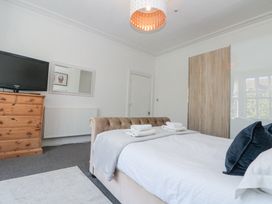 A bedroom with a bed with towels on it a wooden dresser with a television a mirror and a wardrobe at Royal Victoria House in Scarborough