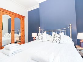 A bedroom with a metal bed frame white bedding folded towels wooden wardrobe with mirrors and bedside lamps at Royal Victoria House in Scarborough