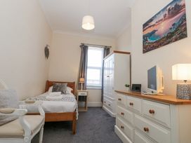 A bedroom with a single bed bedside table armchair wardrobe dresser and a wall picture at Royal Victoria House in Scarborough